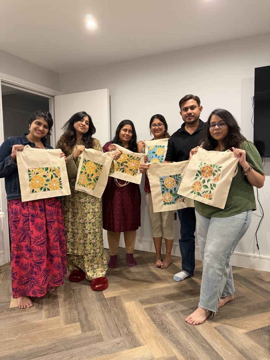 Guests holding up their painted citrus tote bags after the first Paint, Sip & Supper evening