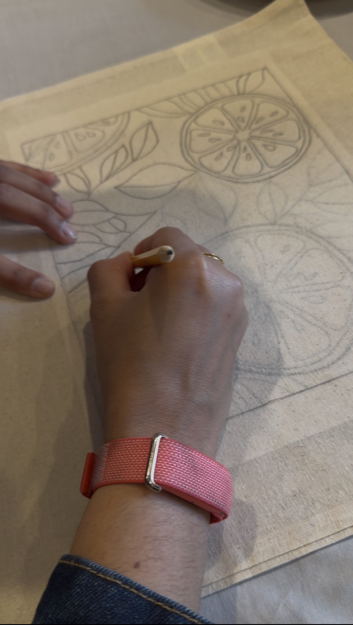 Close-up of a guest tracing the citrus outline onto her tote bag before painting